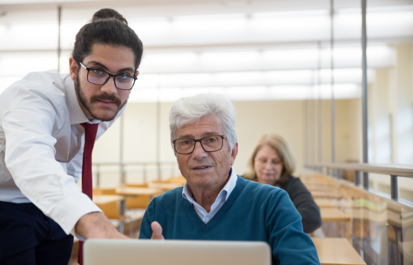 A man and woman collaborating on a laptop, discussing the 20 top traits and skills of top managers.